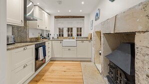 Une cuisine compacte avec des meubles blancs, un four encastré, un évier et une cuisinière noire.