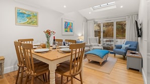 Un coin repas avec une table en bois dressée pour quatre personnes, un canapé et un fauteuil bleu.