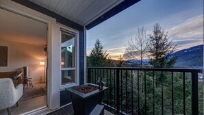 A modern outdoor balcony with a view of mountains and trees.