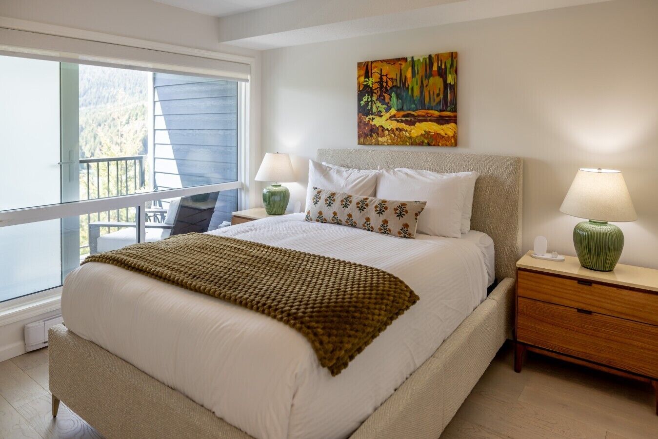 Une chambre à coucher avec un lit, deux tables de chevet, une fenêtre et un tableau au mur.