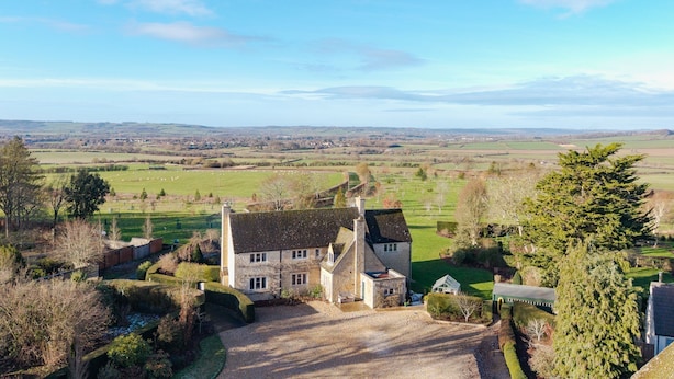 Ein Haus aus Stein mit traditioneller Bauweise, umgeben von einem gepflegten Garten und Blick auf die Landschaft.