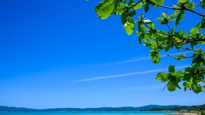 A coastal landscape with a clear sky, a sandy beach, and a view of distant mountains. - Yanbaru Pool Condo Yagaji by COLDIO (Nago)