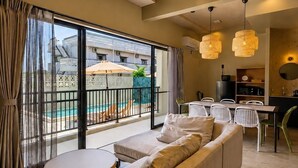 A modern living room with a sofa, round table, and dining area. - Yanbaru Pool Condo Yagaji by COLDIO (Nago)