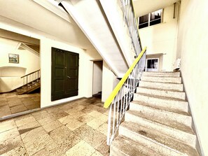 A staircase with a yellow safety line, a closed door, and a small window at the top of the stairs. - Old Town Attic Ignoto 16 SELF CHECK IN (Vilnius)