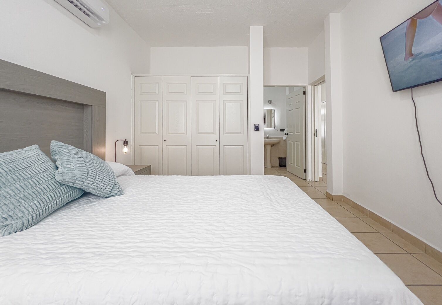 Una camera da letto con un letto grande, un comodino, una TV a muro e un armadio.