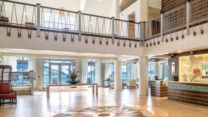 Un hall espacioso con mostrador de recepción, zona de estar y vistas al mar.