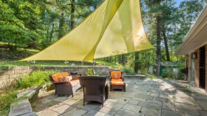 Un patio al aire libre con mobiliario de mimbre y una vela de sombra amarilla.