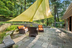 Eine Terrasse im Freien mit Korbmöbeln und einem gelben Sonnensegel.