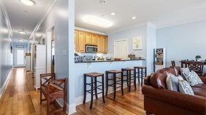 A modern kitchen with wooden cabinets, a microwave, and a bar stool area. - Bay Breeze Bungalow- Winter Rates and Monthly Discounts Available! (Carrabelle)
