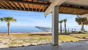 Un’area esterna riparata con vista sul mare e un molo di legno che si protende nell'acqua.