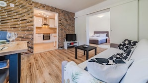 A modern living room with a sofa, a TV, and a dining area with a table and chairs. - The Blue House With Sauna & Jacuzzi (Desinic)