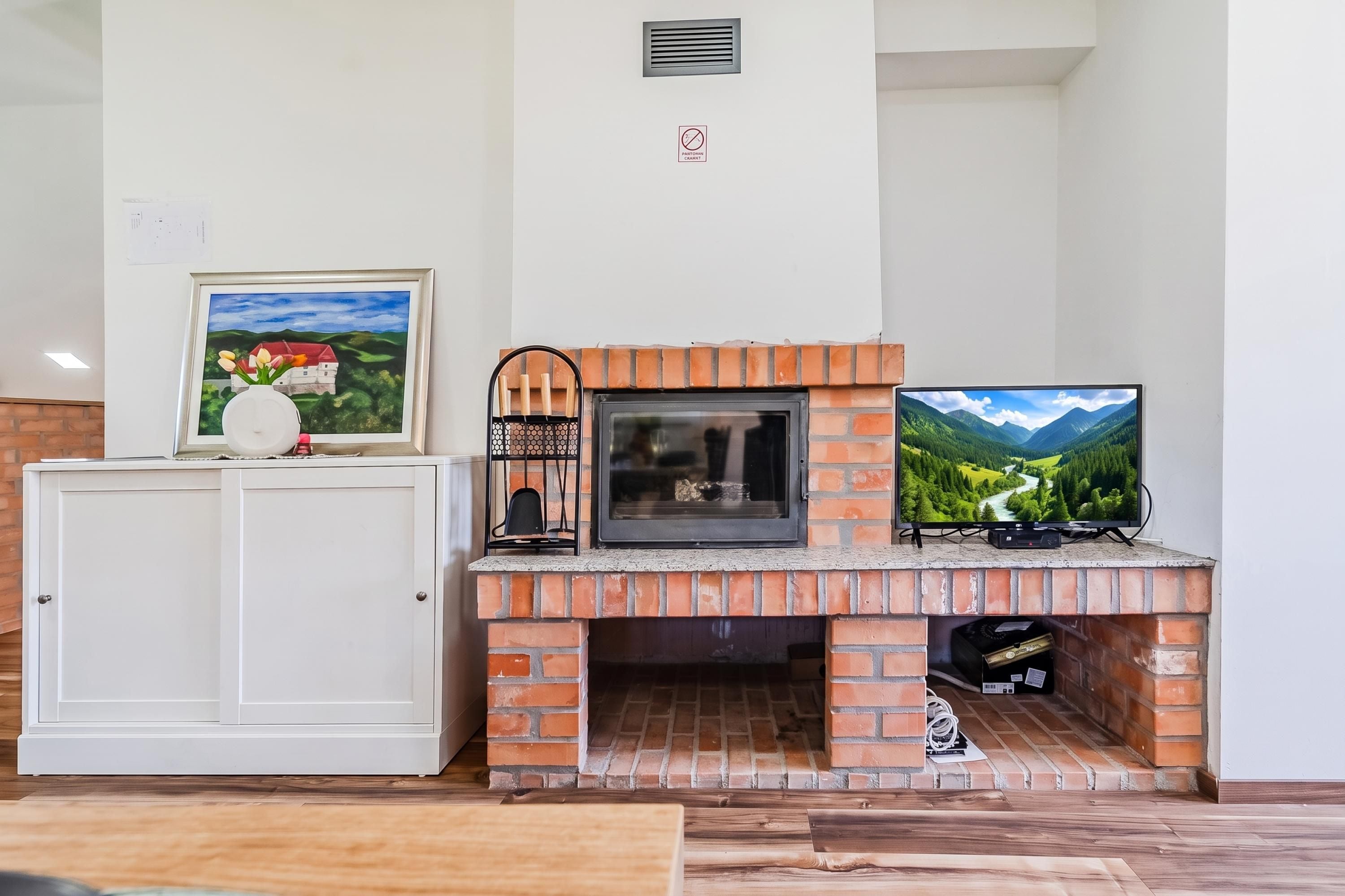 Ein Wohnzimmer mit Kamin, Fernseher und Schrank.