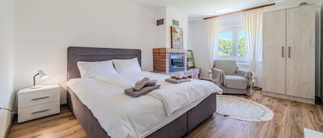 A bedroom with a bed, bedside table, lamp, wardrobe, and a window with curtains.