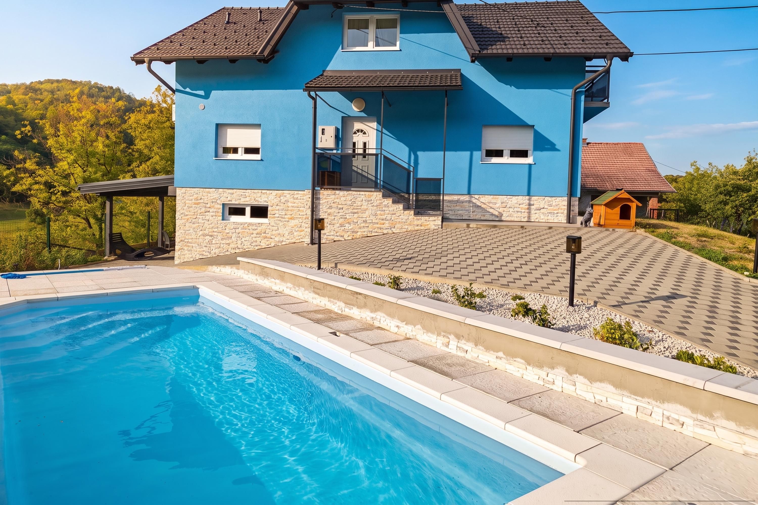 Una casa de dos pisos con piscina, fachada de piedra y una caseta para perro.