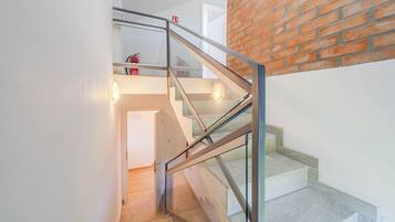 A staircase with glass railings and a brick wall.