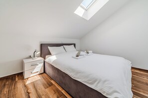 Une chambre à coucher avec un lit, une table de chevet et une lucarne.
