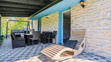 Un patio al aire libre con un muro de piedra, una silla de lounge de madera y mobiliario exterior.