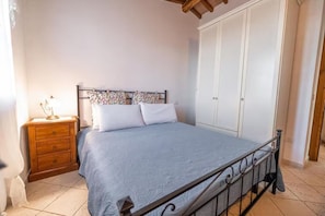 Ein Schlafzimmer mit einem Bett, einem Nachttisch, einem Kleiderschrank und einem Fenster.
