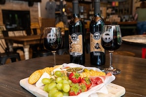 A table with a cheese platter, grapes, strawberries, and prosciutto, accompanied by two wine glasses and three bottles of wine. - Walk to Dining, 1 Mile to SDC, Campfire Pit, Cornhole! (Branson)