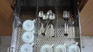 A kitchen drawer with utensils and cups.