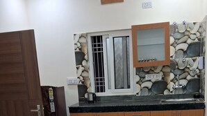 A kitchen with a stone backsplash, wooden cabinets, a sink, and a window with bars.