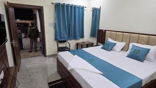 A bedroom with a bed, a ceiling fan, a TV, and a door leading to a balcony.