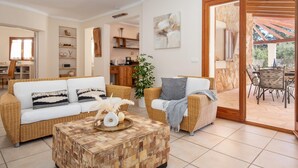 A living room with a sofa, armchairs, a coffee table, and a dining area with chairs and a table. - Villa Sanchez – Comfort and tranquility by the sea. (Santanyi)