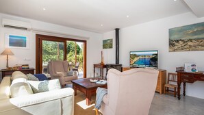 Ein Wohnzimmer mit Sofa, Sessel, Couchtisch und Fernseher, der eine schöne Aussicht zeigt.