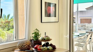 Eine Küchenarbeitsplatte mit einer Ananas, einem Messer, einer Schüssel Artischocken, Tomaten und einer Topfpflanze.