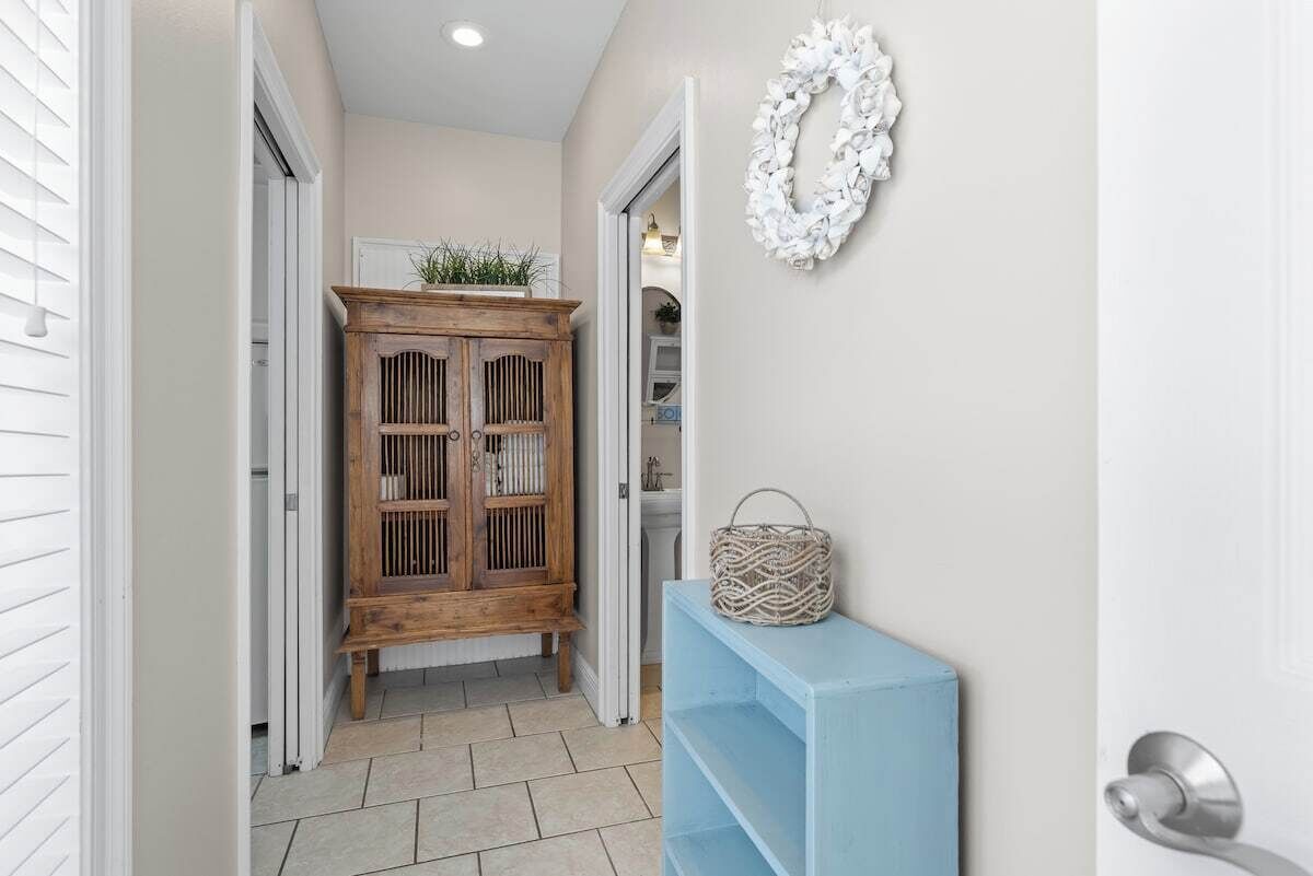 Un couloir avec un meuble en bois, une étagère bleue et un élément décoratif blanc sur le mur.