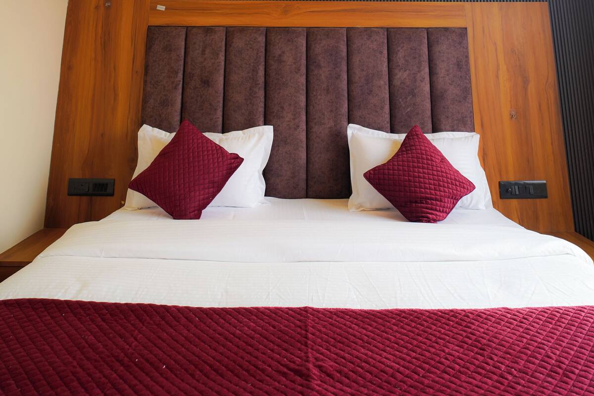 A hotel room with a large bed, a ceiling fan, recessed lighting, and a wooden headboard.