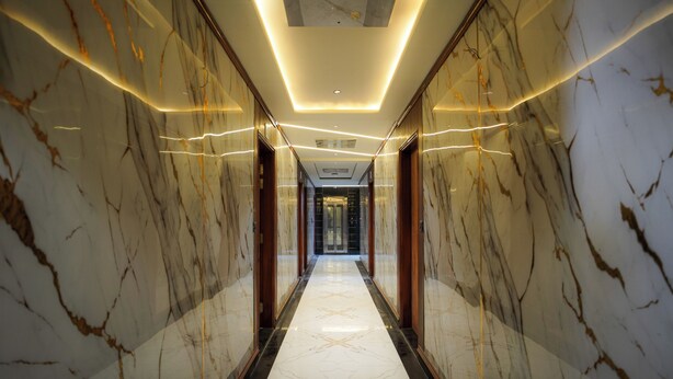 A marble-floored corridor with modern lighting and wooden doors. - THE SPARK INN (Jaipur)