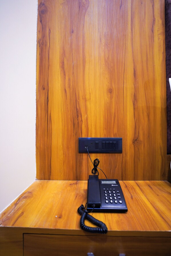 Escritorio de madera con un teléfono y una regleta eléctrica.