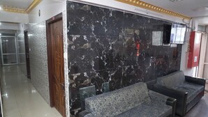 Un hall d’entrée avec un mur de marbre, une porte en bois et deux canapés à motifs.