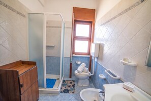 A bathroom with a shower, toilet, bidet, and a wooden cabinet. - Tramonto D'oro Apartment Near The Beach (Porto Cesareo)