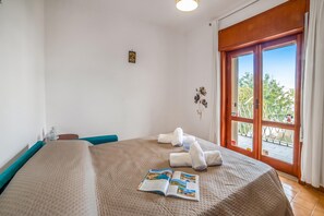 A hotel room with a large bed, a window with a view, and a magazine on the bed. - Tramonto D'oro Apartment Near The Beach (Porto Cesareo)