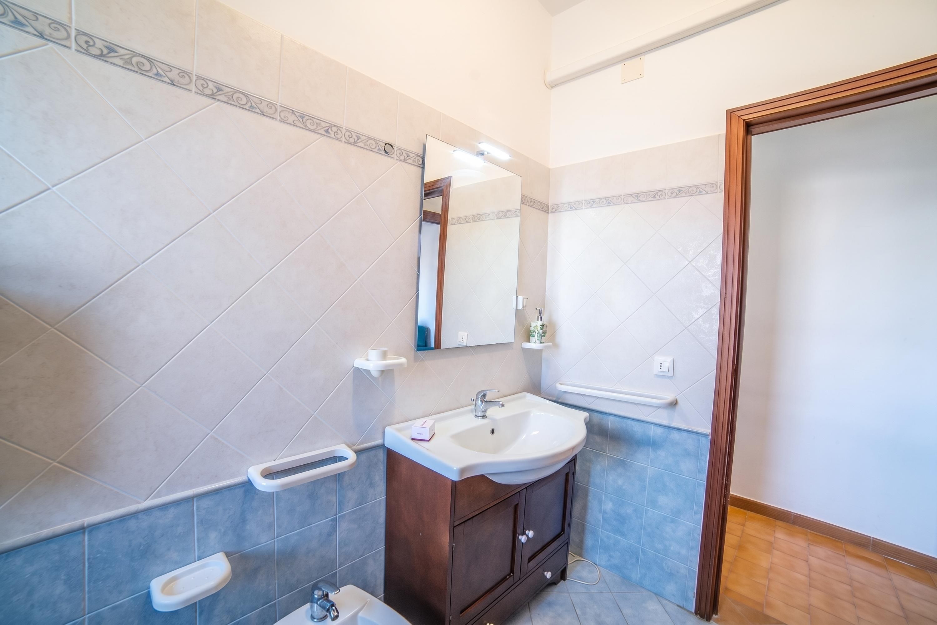 Un baño con un lavamanos blanco, un espejo y un armario de madera.