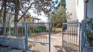 Une entrée fermée par un portail en métal, un chemin pavé et un banc.