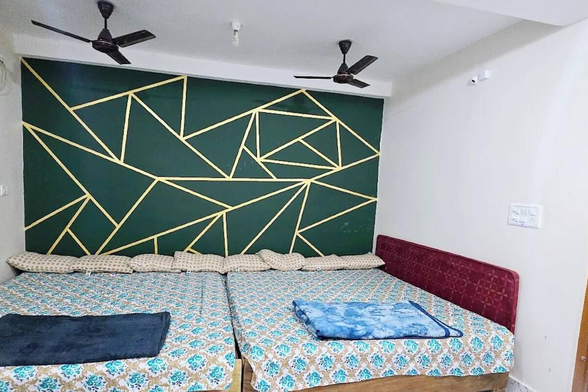 A room with two beds, a geometric-patterned headboard, ceiling fans, and a window with a view.