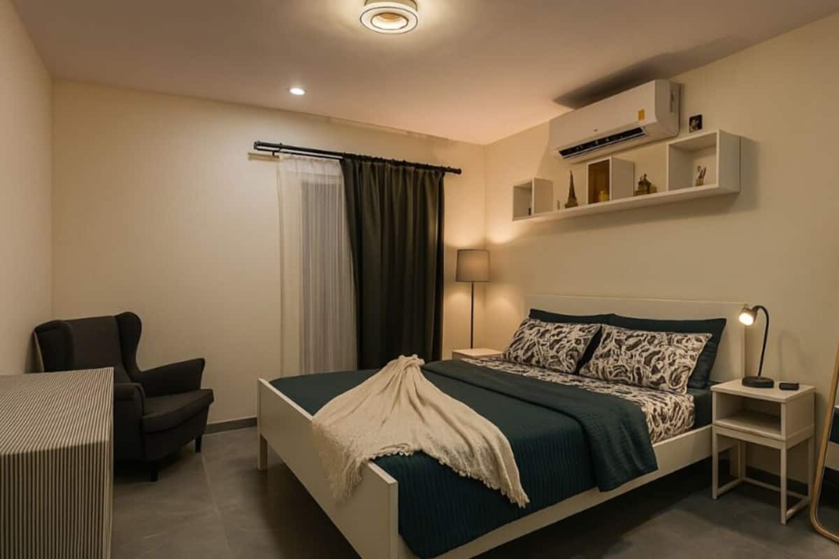 Une chambre d’hôtel moderne équipée d’un lit, d’un bureau, d’une chaise, d’une table de chevet, d’une lampe, d’un miroir et d’un appareil de climatisation.