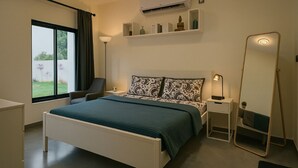 Ein modernes Schlafzimmer mit einem großen Bett, Nachttischen, einer Stehlampe, einem Spiegel und einem Fenster mit Vorhängen.