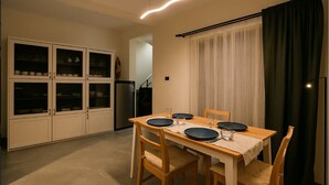 Ein Essbereich mit einem Holztisch, gedeckt für vier Personen, umgeben von Stühlen. Links befindet sich ein Schrank mit Glastüren.