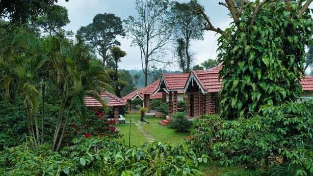 Ein bungalowähnliches Gebäude mit rotem Ziegeldach, umgeben von üppiger Vegetation und einem gepflegten Garten.