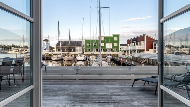 A view from a balcony overlooking a marina with boats, a green building, and a wooden deck. - "Fina" - 10m from the sea by Interhome (Ebeltoft)