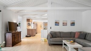 Una sala de estar moderna con un sofá gris, un mueble de madera y un televisor de pantalla plana.