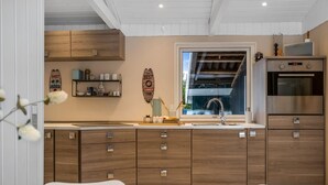 Una cocina moderna con armarios de madera, horno empotrado y ventana con vistas al exterior.