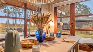 Ein Essbereich mit Holztisch, Stühlen und Blick ins Freie.