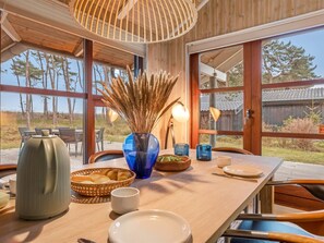 A dining area with a wooden table, chairs, and a view of the outdoors. - "Groa" - 50m from the sea by Interhome (Gedser)