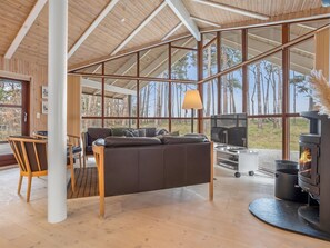 A modern cabin interior with a large wooden ceiling, a sofa, a TV, and a wood stove. - "Groa" - 50m from the sea by Interhome (Gedser)