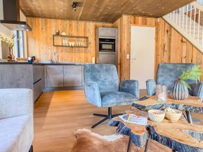 Eine moderne Küche mit Holzelementen, ein Essbereich mit einem rustikalen Tisch und eine Treppe, die zu einer oberen Ebene führt.